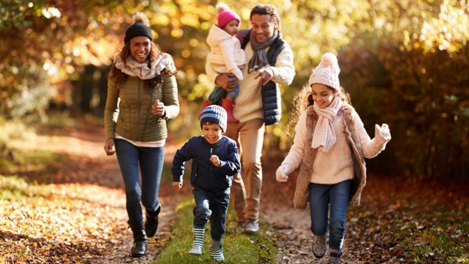 Photo of two parents with their two young children walking together outside dressed in winter gear